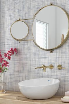 a white sink sitting under a round mirror next to a wall mounted faucet