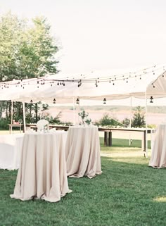 an outdoor tent set up for a wedding reception with tables and chairs covered in white cloths