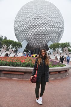 a woman standing in front of a large ball at the epcoti disney world