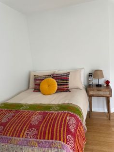 a bed sitting in a bedroom next to a wooden table with a lamp on top of it