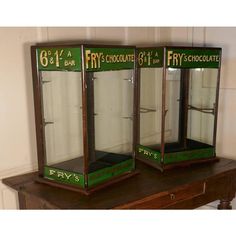 two old fashioned refrigerators sitting on top of a wooden table