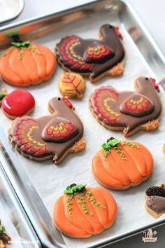 decorated cookies in the shape of turkeys and pumpkins on a baking sheet, ready to be eaten