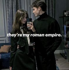 a man and woman standing next to each other in front of a window with the caption they're my roman empire