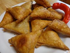 some fried food on a white plate with a red pepper