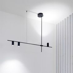 three lights are hanging from the ceiling in a room with white walls and vertical blinds