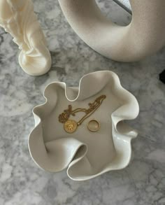 a white vase and ring dish on a marble table