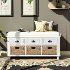 a white bench with baskets underneath it and pictures on the wall