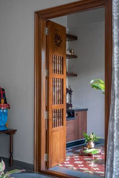 an open wooden door in front of a kitchen with a potted plant next to it