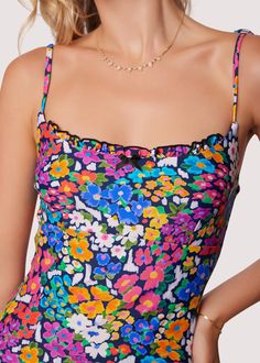 ELIGIBLE FOR RETURNS OR EXCHANGES Start your vacation with a beach view in the Renoir's Terrace Ruffle One-Piece Swimsuit! This floral inspired pattern is featured in an array of spring colors to bring charisma as you dip your toes into the sand. The bust features a a small ruffle trim and sweet bow for a feminine touch. Adjustable strap tie details are found at the shoulder for better support! Style # WMKC09047 Imported 80% Nylon, 20% Spandex Model is 5 ft 9 inches; Bust: 32", Waist: 23.5", Hip Printed One-piece Swim Dress For Sunbathing, Beachy Sleeveless Tankini For Summer Parties, Sleeveless Tankini For Summer Parties And Vacation, Vacation Tankini For Summer Parties, Tropical Ruffled Tankini For Beach Season, Summer Floral Print Swimwear For Summer Parties, Floral Print Summer Swimwear For Parties, Floral Print Sleeveless Swimwear For Sunbathing, Sleeveless Ruffled Swimwear For Vacation