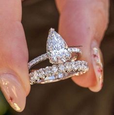 a woman's hand holding two wedding rings with diamond bands on it and the ring is shaped like a butterfly