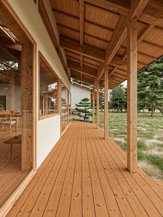 an empty wooden porch with chairs and tables on the outside deck, looking out onto a grassy field