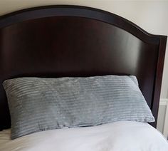 a bed with white sheets and pillows on top of it