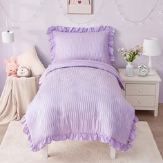 a purple bed with ruffled sheets and pillows