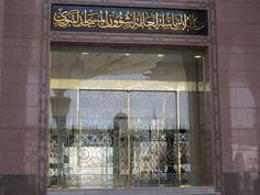 a store front with arabic writing on the window and an open fire hydrant in front