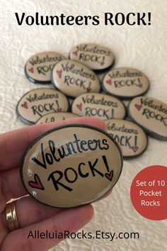 a hand holding a rock with volunteer's rock written on it and the words volunteer's rock set of 10 pocket rocks