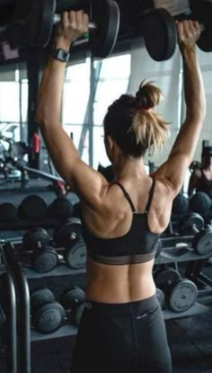 a woman lifting two dumbbells in a gym