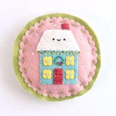 a pink and green felt ornament with a house on it