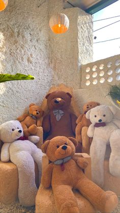 a group of teddy bears sitting on top of a couch in a room with lights hanging from the ceiling