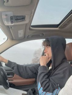 a man sitting in the driver's seat of a car talking on his cell phone