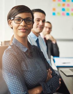 an attractive business woman standing in front of her team at the office with her arms crossed