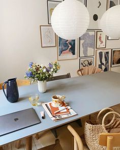 a dining room table and chairs with pictures on the wall behind it, along with a laptop