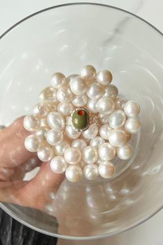 a person holding a bunch of pearls in a glass bowl