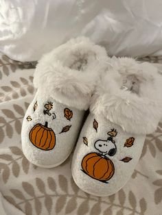 a pair of white slippers with cartoon pumpkins on them sitting on a bed