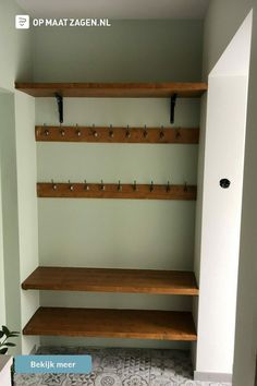 an empty walk - in closet with wooden shelves and hooks on the wall, next to a potted plant