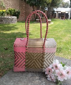 two woven bags sitting on the ground next to flowers