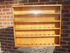 a wooden shelf sitting on top of a metal object in front of a brick wall