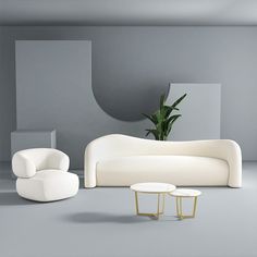 a white couch and two tables in a room with gray walls, grey flooring and a potted plant