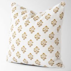 a white and gold pillow with an ornate design