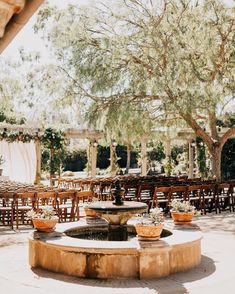 an outdoor wedding venue set up with tables, chairs and water feature in the center