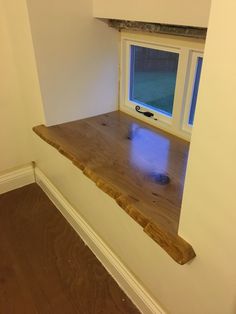 an empty room with a window and wooden shelf