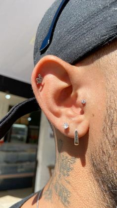 a close up of a person wearing ear piercings and a hat with tattoos on it