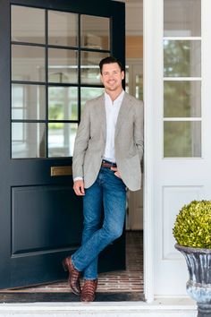 a man standing in front of a door with his hands in his pockets and smiling