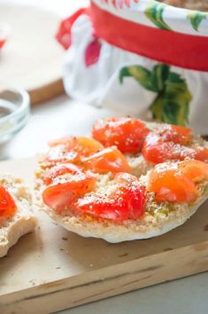 two pieces of bread with tomatoes on them sitting on a cutting board next to a bowl