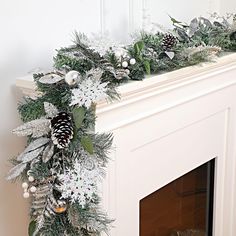 a fireplace mantel decorated with silver and white christmas decorations