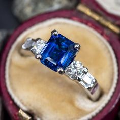 a blue and white diamond ring sitting in a velvet box on top of a table