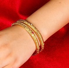 Antique gold-plated bangle from Amrapali is a masterpiece of South Indian jewelry. Known as a Kada bracelet, it features traditional jadau craftsmanship and Kemp stones, making it ideal for temple and bridal wear. This exquisite piece serves as a timeless gift, embodying the rich cultural heritage of India. *𝐏𝐑𝐎𝐃𝐔𝐂𝐓 𝐃𝐄𝐓𝐀𝐈𝐋* * Material: Brass * Plating: Gold Plated *𝐃𝐈𝐌𝐄𝐍𝐒𝐈𝐎𝐍𝐒* * Weight: 15 gm * Width: 0.2 Inches     *𝐃𝐈𝐒𝐂𝐋𝐀𝐈𝐌𝐄𝐑* Product color may slightly vary du Elegant Bangle For Navratri, Elegant Bangle Bracelet For Navratri, Festive Yellow Gold Bracelets For Festivals, Festive Gold Temple Bangle Bracelet, Elegant Gold Bracelet For Navratri, Elegant Gold Bangle For Navratri, Elegant Gold Bracelets For Navratri, Festive Gold Temple Jewelry Bangle, Festive Temple Jewelry Gold Bangle