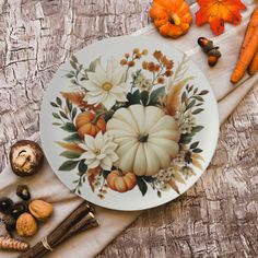 a plate decorated with flowers and pumpkins sits on a table next to other autumn decorations