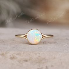 a white opal ring sitting on top of a stone slab with the words,