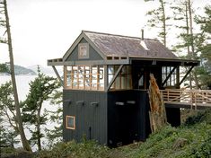 a small black building sitting on top of a lush green hillside