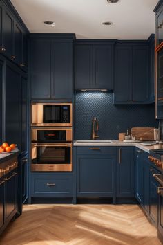 a kitchen with blue cabinets and wood flooring is pictured in this image, there are two ovens on the counter