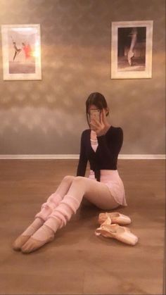 a woman sitting on the floor covering her face with her hands while holding ballet shoes