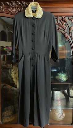 "Beautiful slightly textured black crepe dress with matching covered buttons down the front. About above ankle length at 48\" long from top of shoulder to hem. 20\" pit to pit and 14.5\" across waist when lying flat. Pretty pale blue sheer collar with velvet piping and iridescent sequins." Black Long Sleeve Dress With Hidden Button Closure, Black Cocktail Dress With Button Closure, Black Evening Dresses With Button Closure, Classic Black Dresses With Hidden Button Closure, Black Button-back Dress For Work, Black Buttoned Midi Dress For Semi-formal Occasions, Black Semi-formal Midi Dress With Buttons, Black Semi-formal Dress With Button Closure, Semi-formal Black Midi Dress With Buttons