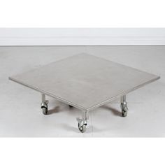 a square metal table with four wheels on the bottom and one foot in the middle