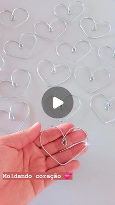 a hand holding a heart shaped object in front of many other hearts on a table