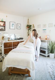 a woman in white shirt standing next to a bed