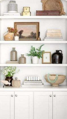 a white book shelf with books and vases sitting on it's top shelves